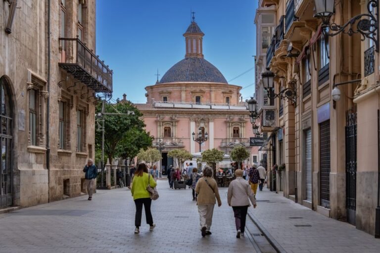 Encantadora calle en Valencia con arquitectura histórica y personas disfrutando del día.