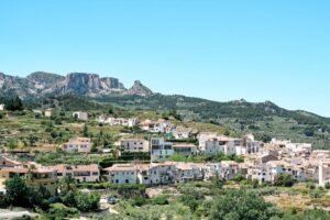 Pueblo pintoresco con arquitectura mediterránea situado contra un exuberante telón de fondo montañoso.