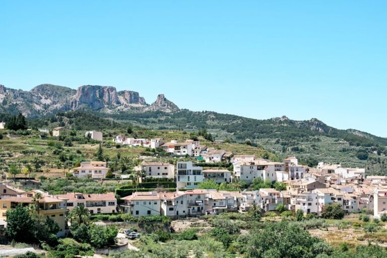 Pueblo pintoresco con arquitectura mediterránea situado contra un exuberante telón de fondo montañoso.