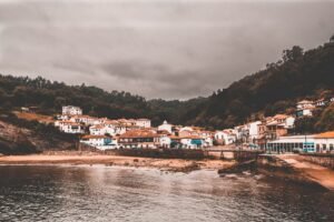 Encantador pueblo costero de Candás, España, bajo cielos nublados con casas tradicionales a lo largo de la costa.