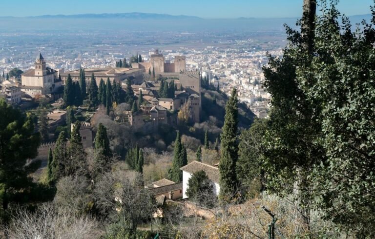 Impresionante vista de la Alhambra con el paisaje urbano de Granada en España, rodeada de exuberantes cipreses.