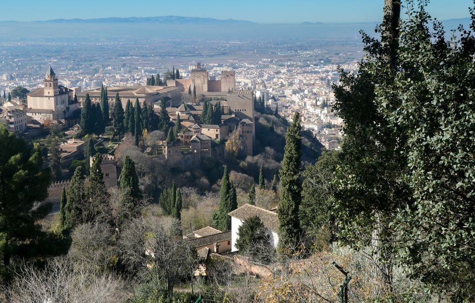 Impresionante vista de la Alhambra con el paisaje urbano de Granada en España, rodeada de exuberantes cipreses.