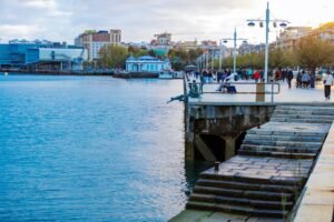 Escena animada de waterfront con personas disfrutando del paseo junto al mar al anochecer.