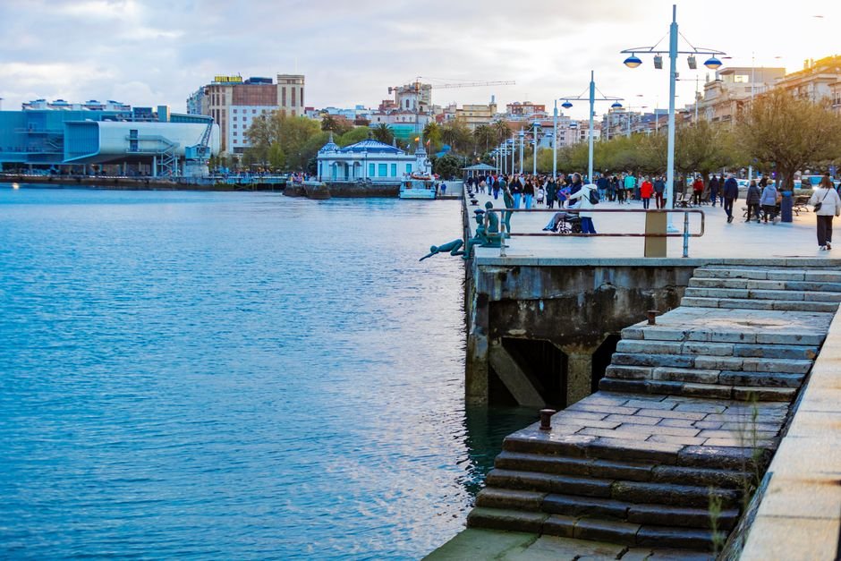 Escena animada de waterfront con personas disfrutando del paseo junto al mar al anochecer.